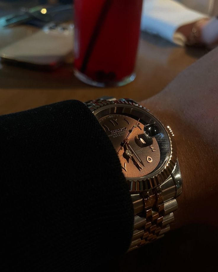 Montre en or et acier portée au poignet sur une table de bar